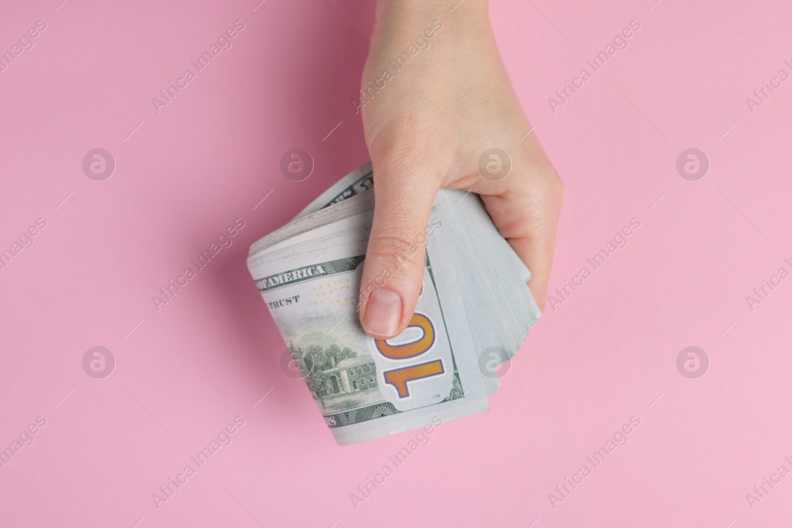 Photo of Money exchange. Woman holding dollar banknotes on pink background, top view