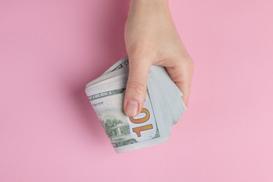 Photo of Money exchange. Woman holding dollar banknotes on pink background, top view