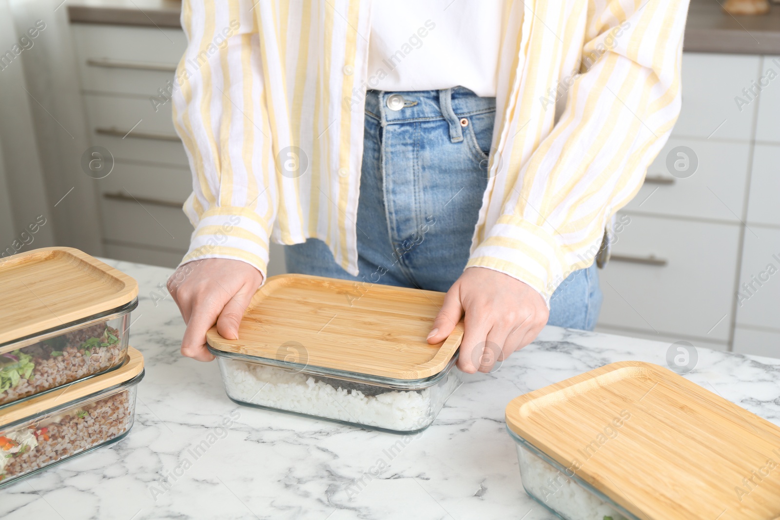 Photo of Healthy food. Woman closing glass container with meal at white marble table, closeup