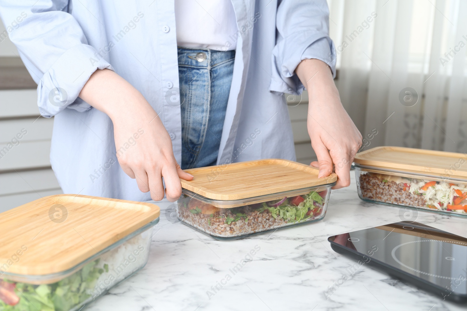 Photo of Healthy food. Woman closing glass container with meal at white marble table, closeup