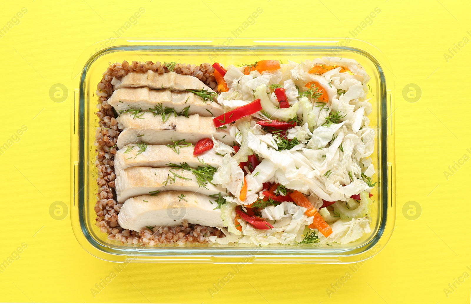 Photo of Healthy meal. Fresh salad, chicken and buckwheat in glass container on yellow background, top view