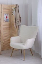 Photo of Folding screen, clothes and armchair in room