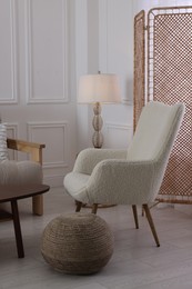 Folding screen, armchair, pouffe and lamp in room