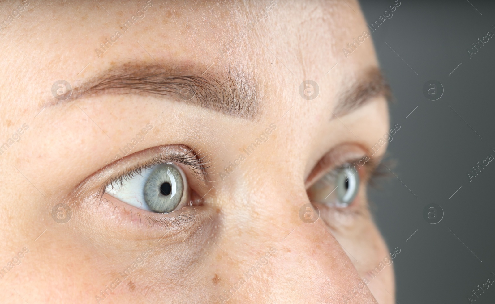 Photo of Woman with beautiful blue eyes on grey background, closeup