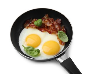 Photo of Fried eggs, bacon and basil in frying pan isolated on white