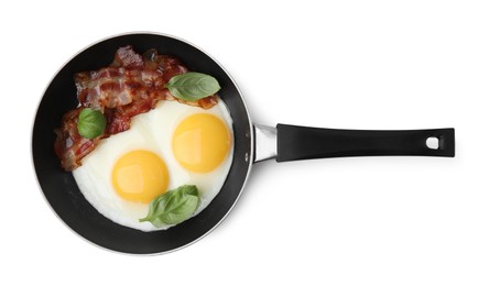 Photo of Fried eggs, bacon and basil in frying pan isolated on white, top view