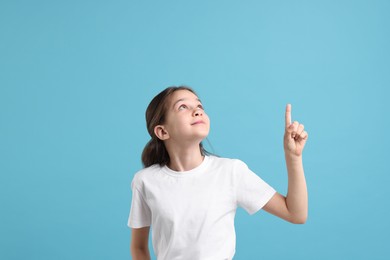 Photo of Beautiful girl pointing at something on light blue background
