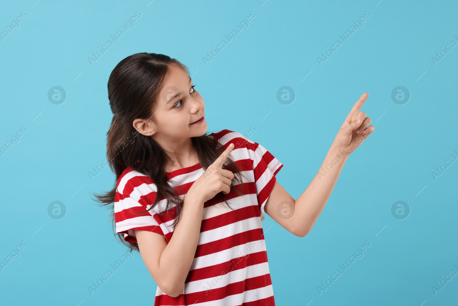 Photo of Beautiful girl pointing at something on light blue background