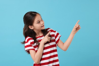 Photo of Beautiful girl pointing at something on light blue background