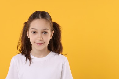 Portrait of beautiful girl on orange background, space for text