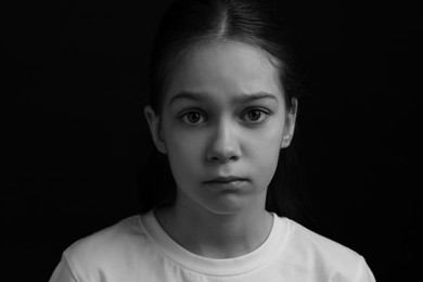 Portrait of sad girl in darkness, closeup. Black and white effect