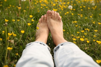 Woman sitting barefoot on green grass outdoors, closeup