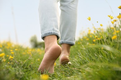 Woman walking barefoot on green grass outdoors, closeup