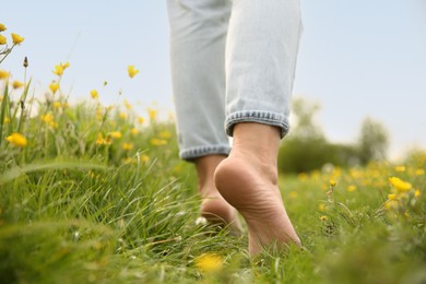 Photo of Woman walking barefoot on green grass outdoors, closeup