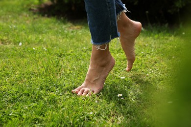 Woman walking barefoot on green grass outdoors, closeup