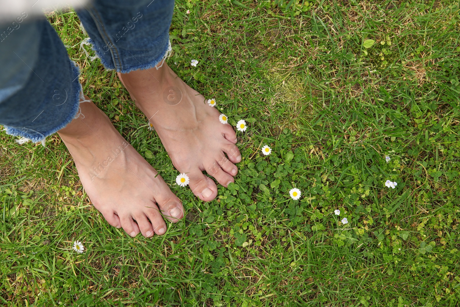 Photo of Woman walking barefoot on green grass outdoors, top view. Space for text