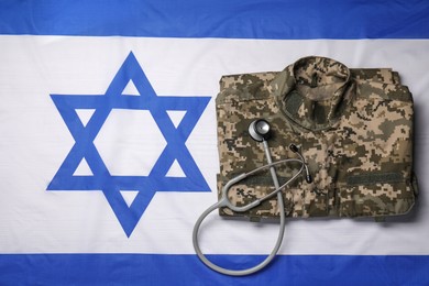 Stethoscope and military uniform on flag of Israel, top view