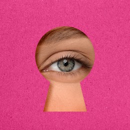 Woman looking through keyhole in pink surface