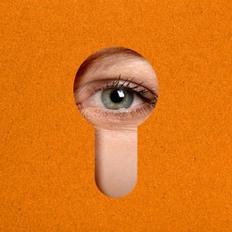 Woman looking through keyhole in orange surface