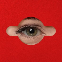 Woman looking through keyhole in red surface