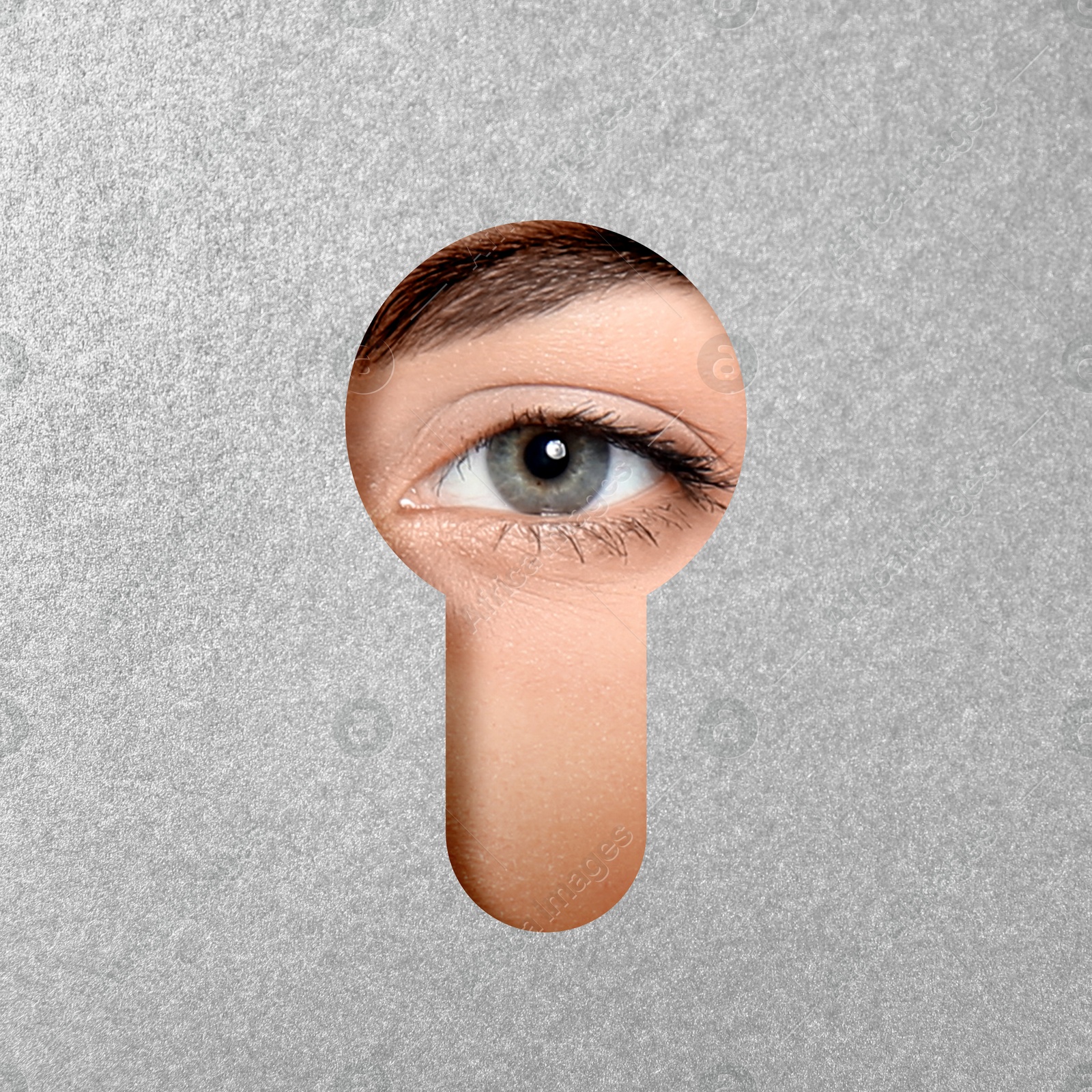 Image of Woman looking through keyhole in grey surface