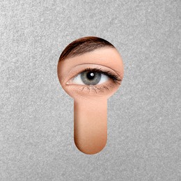 Image of Woman looking through keyhole in grey surface