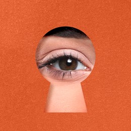 Woman looking through keyhole in dark orange surface