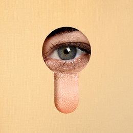 Woman looking through keyhole in beige surface