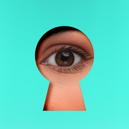 Woman looking through keyhole in cyan surface