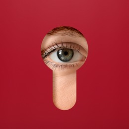 Woman looking through keyhole in red surface