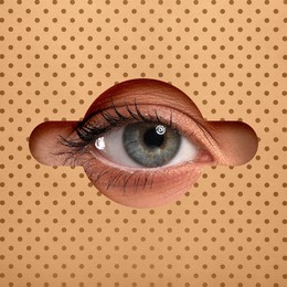 Woman looking through keyhole in beige dotted surface