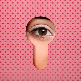 Image of Woman looking through keyhole in pink dotted surface