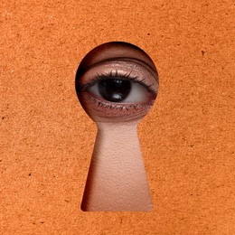 Image of Woman looking through keyhole in dark orange surface