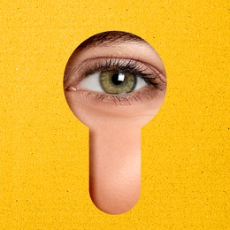 Woman looking through keyhole in yellow surface