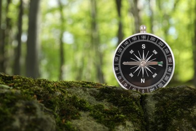 Navigational instrument. Compass in forest, closeup. Space for text