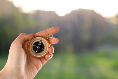 Image of Woman holding compass in nature, closeup. Navigational instrument