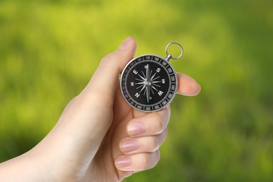 Woman holding compass in nature, closeup. Navigational instrument