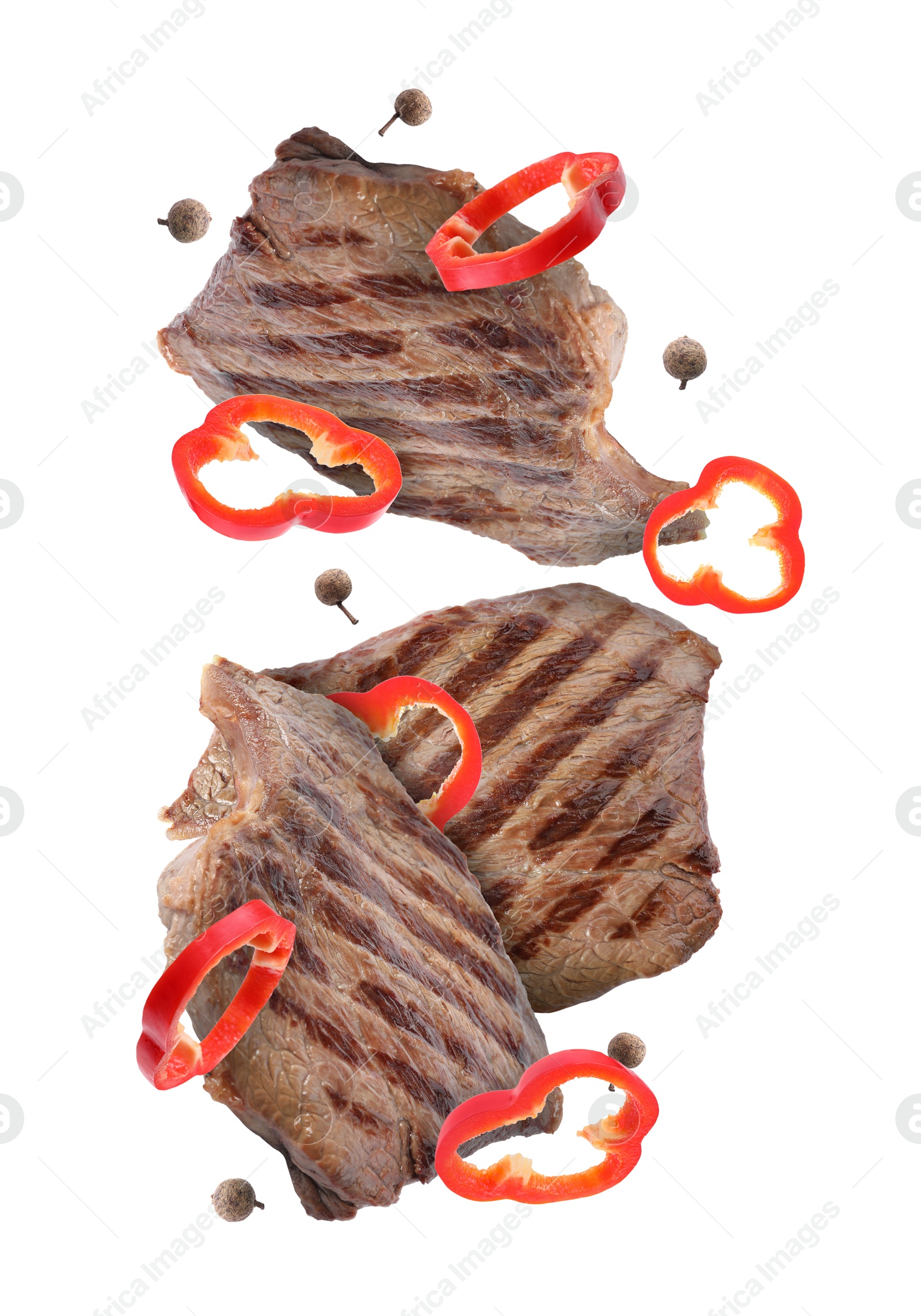 Image of Grilled beef steaks, pepper slices and peppercorns in air isolated on white