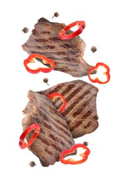 Image of Grilled beef steaks, pepper slices and peppercorns in air isolated on white