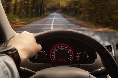 Man driving car with one hand on steering wheel, closeup