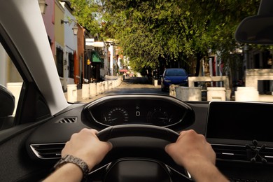 Image of Driving car, view from driver's seat. Man holding hands on steering wheel, closeup