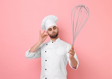 Happy pastry chef with big whisk on pink background