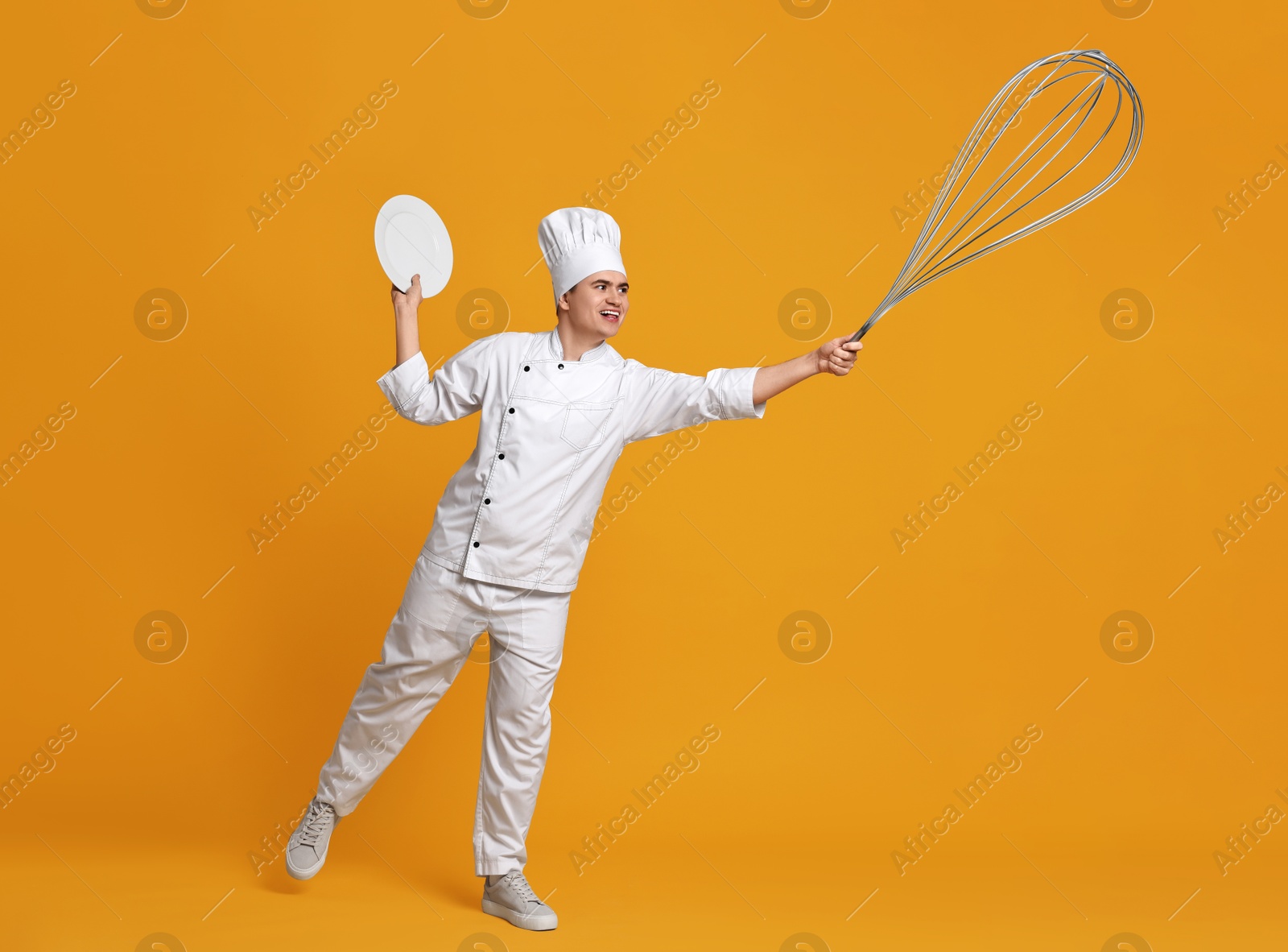 Image of Pastry chef with big whisk and plate on orange background