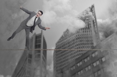 Image of Concentrated businessman balancing on rope over city. Concept of risk