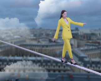 Concentrated businesswoman walking rope over city. Concept of risk and balance