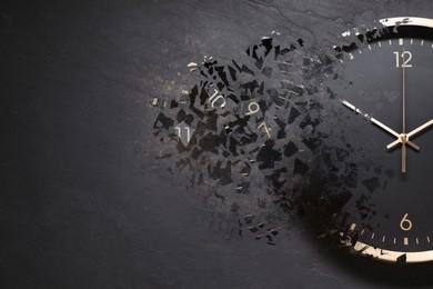 Image of Black clock shattering into pieces on black background. Flow of time