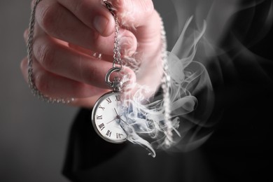 Image of Businessman holding dissolving chronometer on grey background, closeup. Time is running out