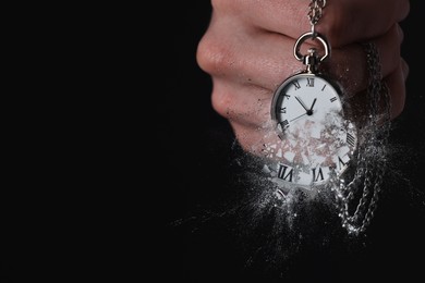 Image of Businessman holding dissolving chronometer on black background, closeup. Time is running out