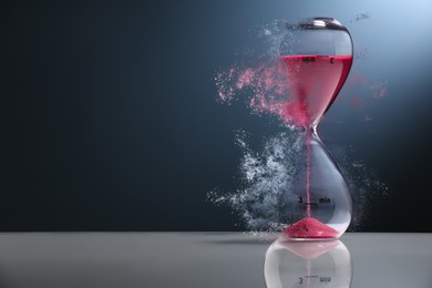 Image of Hourglass dissolving on table against dark background. Fleeting time