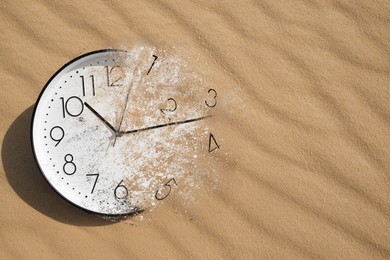 Image of Analog clock dissolving among desert. Time is running out
